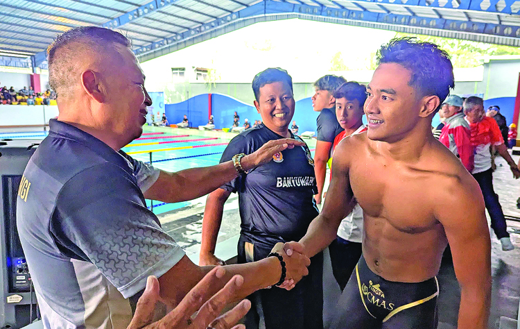 Ketua KONI Banyuwangi Ahmad Khoirullah menyalami Mochamad Maulana Rahman yang berhasil memecahkan rekor di nomor surface 50 meter di GOR Gajayana, Senin (30/6).