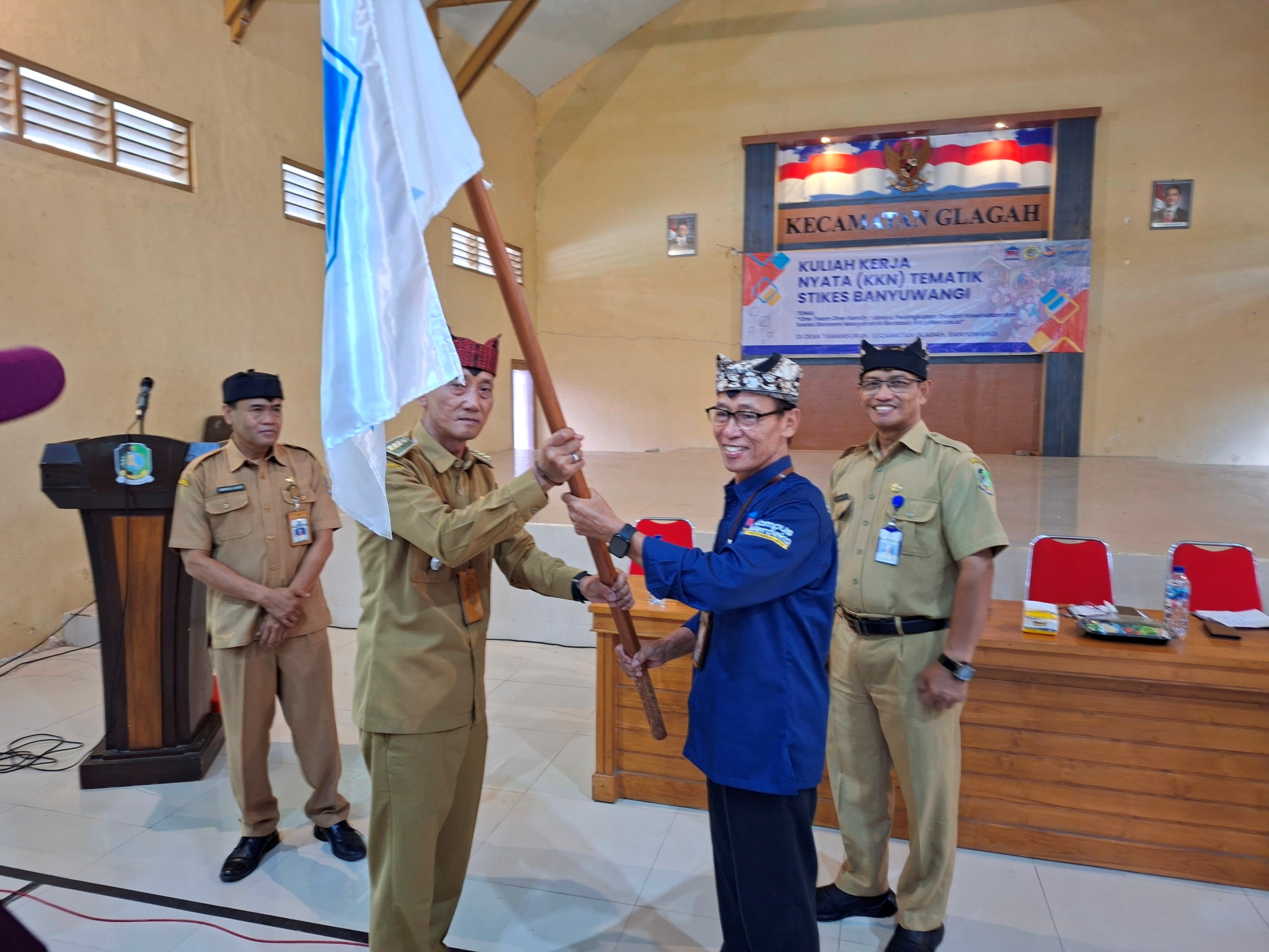 SIMBOLIS: Ketua Stikes Banyuwangi Dr H Soekardjo (kanan) menyerahkan bendera Kepada Camat Glagah Joko Kuncoro sebagai tanda dimulainya KKN Tematik OTOF di Desa Tamansuruh, Glagah, Senin (30/6).