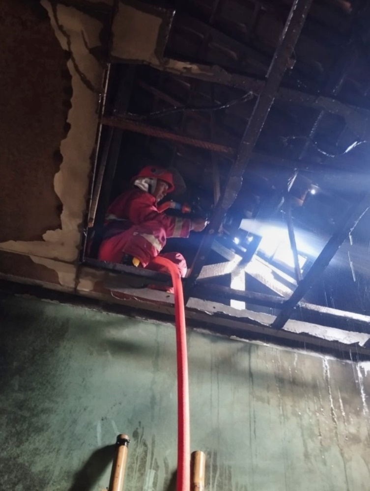 PEMADAMAN: Anggota Damkarmat Bangorejo Agus Rifai memanjat plafon dapur untuk memadamkan api di rumah Dayu Ernita di Dusun Sumbersuko, Desa Kesilir, Kecamatan Siliragung Kamis (10/7).