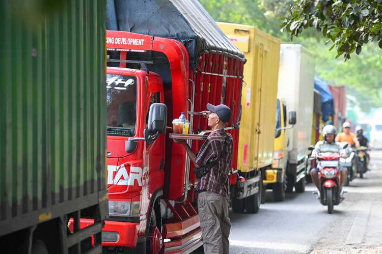 Penjual es keliling menawarkan dagangannya ke sopir truk yang terjebak kemacetan panjang di jalur Wongsorejo-Ketapang.