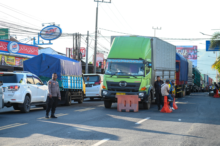 TERJEBAK MACET: Aparat kepolisian mengatur kepadatan arus kendaraan yang didominasi truk besar di jalan arteri sebelah utara Pelabuhan ASDP Ketapang, Senin (21/7).