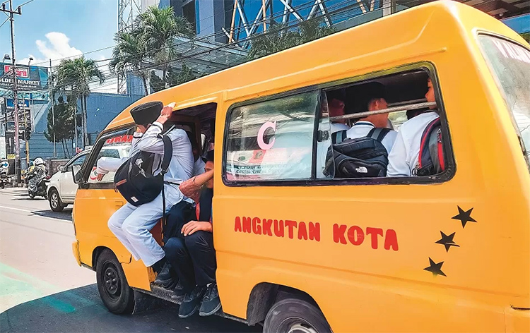 Siswa berseragam putih-putih naik angkot sepulang sekolah, di Jalan Trunojoyo, Jember.