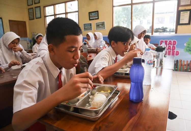 Siswa SDN 1 Genteng menikmati makan bergizi gratis saat jam istirahat di sekolahnya, Selasa (22/7).