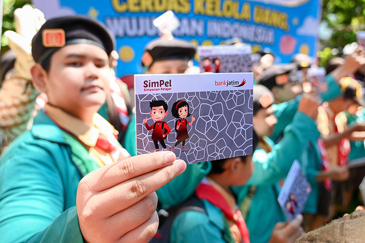 MENABUNG SEJAK DINI: Pelajar sekolah dasar menunjukkan buku rekening tabungan Simpel Bank Jatim.