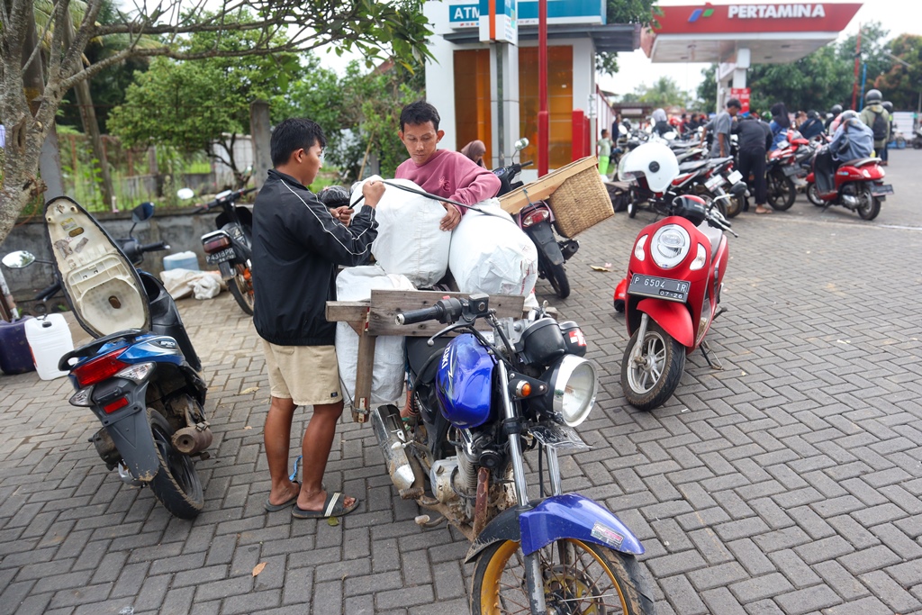 Warga Jember menata jeriken berisi BBM untuk dibawa menggunakan sepeda motornya.