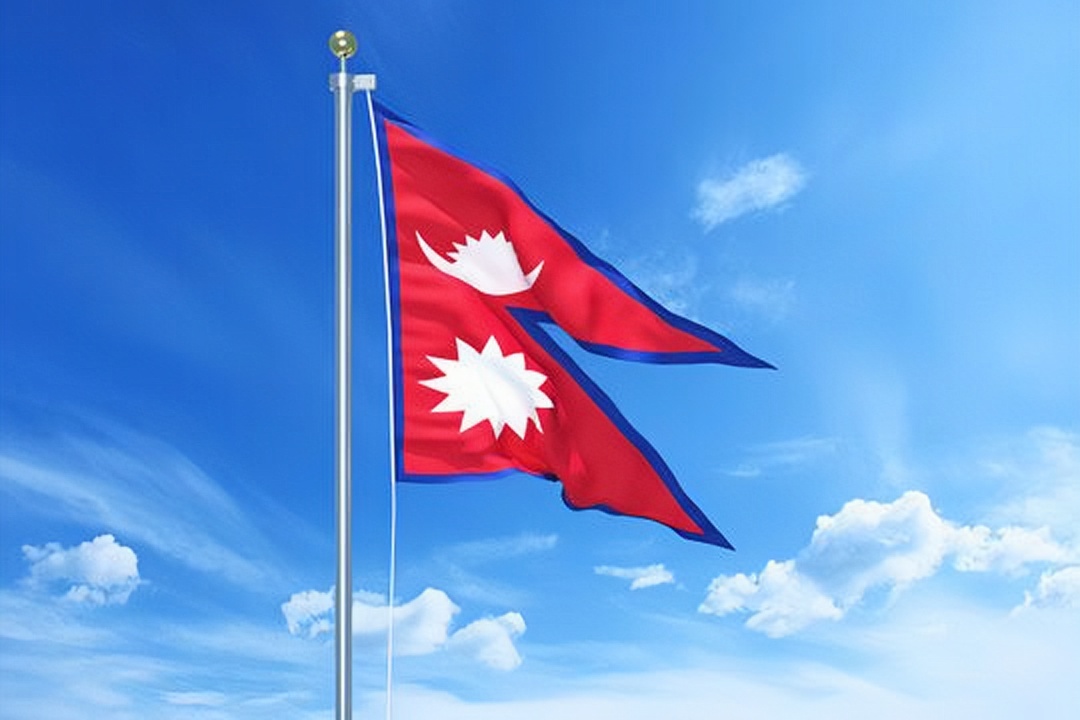 Bendera nasional Nepal berkibar dengan desain dua segitiga vertikal, menjadi satu-satunya bendera negara di dunia yang tidak berbentuk persegi panjang.