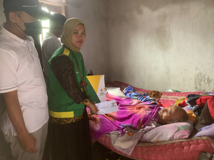 Petugas Baznas menyerahkan bantuan kepada Paijan yang tengah terbaring sakit di kediamannya di Desa Kaligondo, Kecamatan Genteng (foto kiri).