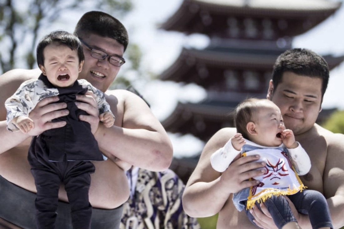 Dua bayi menangis di gendongan pegulat sumo