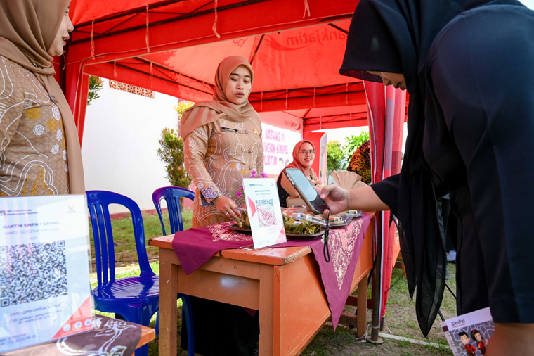 CASHLESS: Siswa SMPN 1 Srono melakukan pembayaran memanfaatkan QRIS usai berbelanja di stand penjualan makanan dan minuman, Kamis (7/8).
