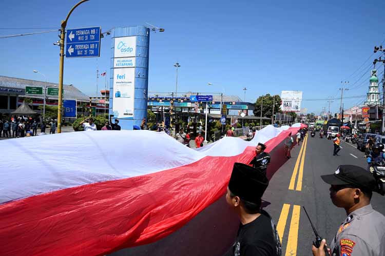 Sopir truk yang tergabung dalam Gerakan Sopir Jawa Timur (GSJT) membentangkan bendera merah putih sepanjang 500 meter di depan Pelabuhan Ketapang, Rabu (6/8).