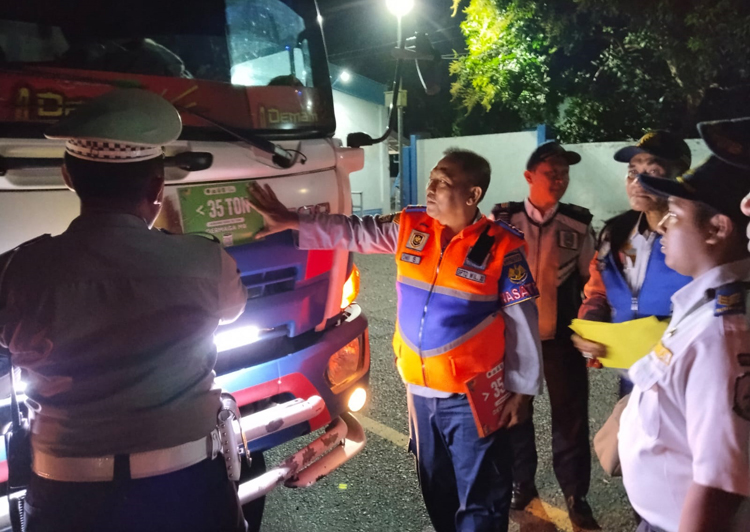 MULAI DIPASANG: Petugas Dishub Banyuwangi menempel stiker di truk saat melintasi jembatan timbang Watudodol, Kamis malam (7/8).