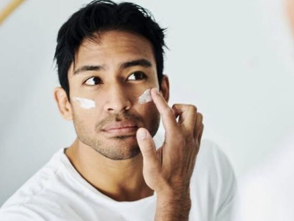 pria mengaplikasikan sunscreen pada wajah