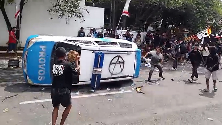 Mobil polisi dijungkirbalikkan massa sebelum dibakar dalam demo 13 Agustus di Pati, Jawa Tengah.