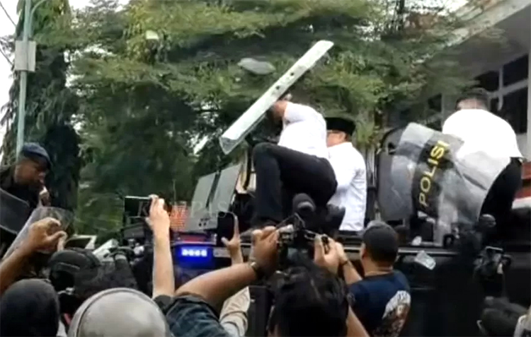 Aparat melindungi Bupati Sudewo menggunakan tameng dari lemparan sandal massa, Rabu (13/8/2025).
