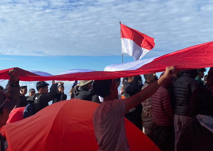 Ratusan orang membentangkan bendera merah putih sepanjang 5 meter di puncak Gunung Ranti untuk memperingati HUT ke-80 Kemerdekaan RI, Minggu (17/8).