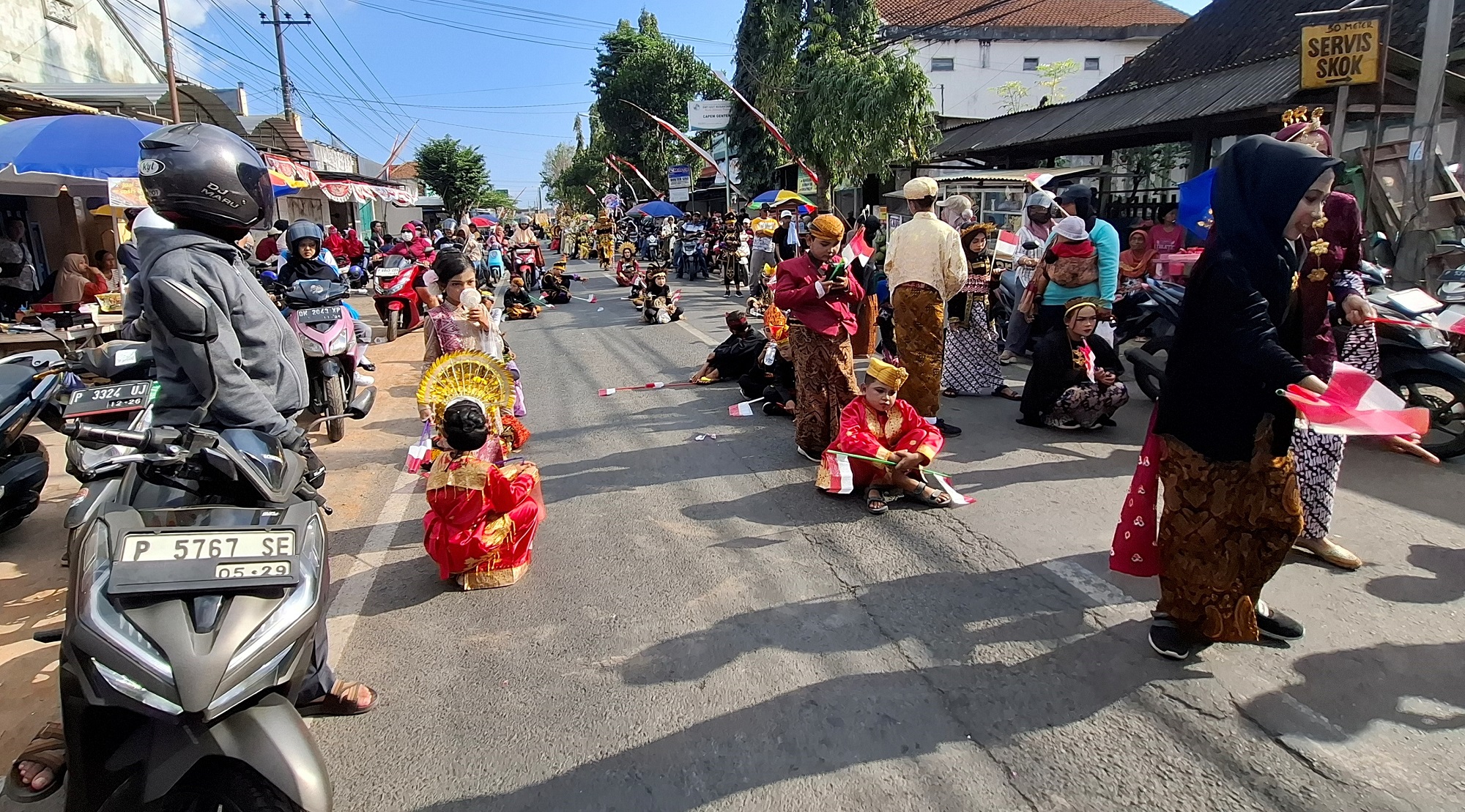 Para peserta karnaval dari Gugus Desa Genteng Wetan, Kecamatan Genteng duduk-duduk di jalan membuat lalu lintas semakin macet.