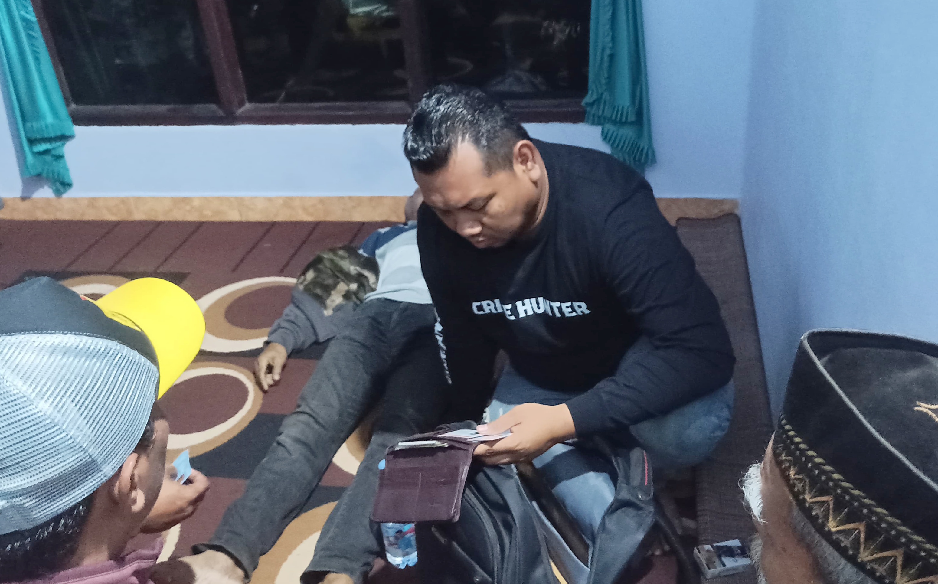 Anggota Unit Reskrim Polsek Genteng mengecek kondisi jenazah Mustofa di rumah pasiennya Dusun Kaliputih, Desa Genteng Wetan pada Selasa (26/8) malam.