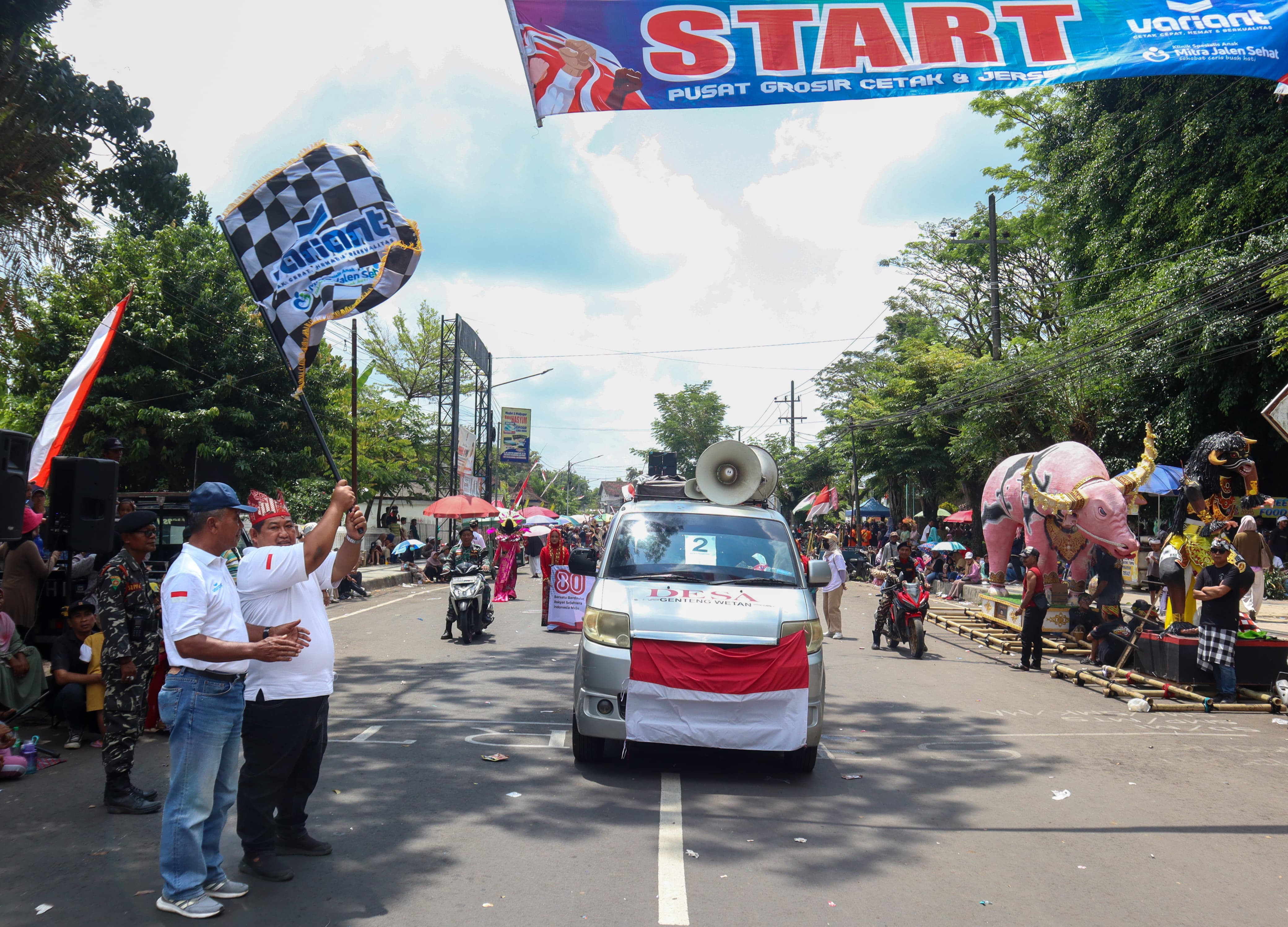 BUDAYA: Eko Priyono alias Oce pegang bendera, bersama Ketua Panitia HUT RI ke-80 Kecamatan Genteng, H. Nurhadi memberangkatkan peserta karnaval Minggu (31/8).
