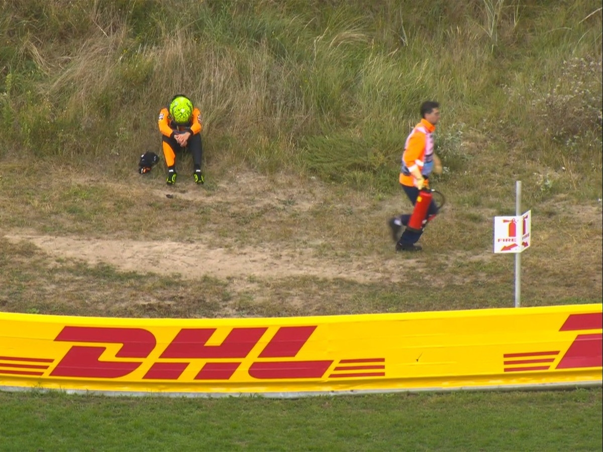 Lando Norris terduduk di tepi Sirkuit Zandvoort usai mobil F1 McLaren yang dikendarainya tak bisa melanjutkan balapan.