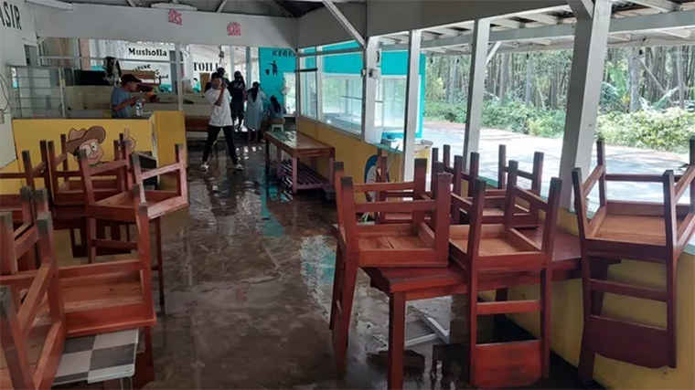 BERSIH-BERSIH: Ibu Shanty, pemilik warung di puncak Gumitir (Watu Gudang) bersihkan sampah daun yang ada di depan warungnya, Senin (1/9).