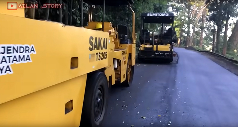 Alat berat meratakan aspal baru di jalur Gumitir Banyuwangi-Jember.