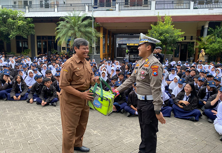 SOSIALISASI: Kanit Regident Polresta Banyuwangi AKP Satria Ari menyerahkan rompi lalu lintas kepada Plt. Kepala SMPN 1 Banyuwangi Sugeng Lukito, Selasa (9/9).