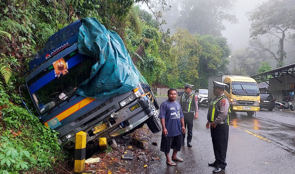Unit Lantas Polsek Kalibaru memeriksa truk yang mengalami kecelakaan di tikungan Patung Gandrung, Dusun Sumber Beringin, Desa Kalibaru Manis, Kecamatan Kalibaru.