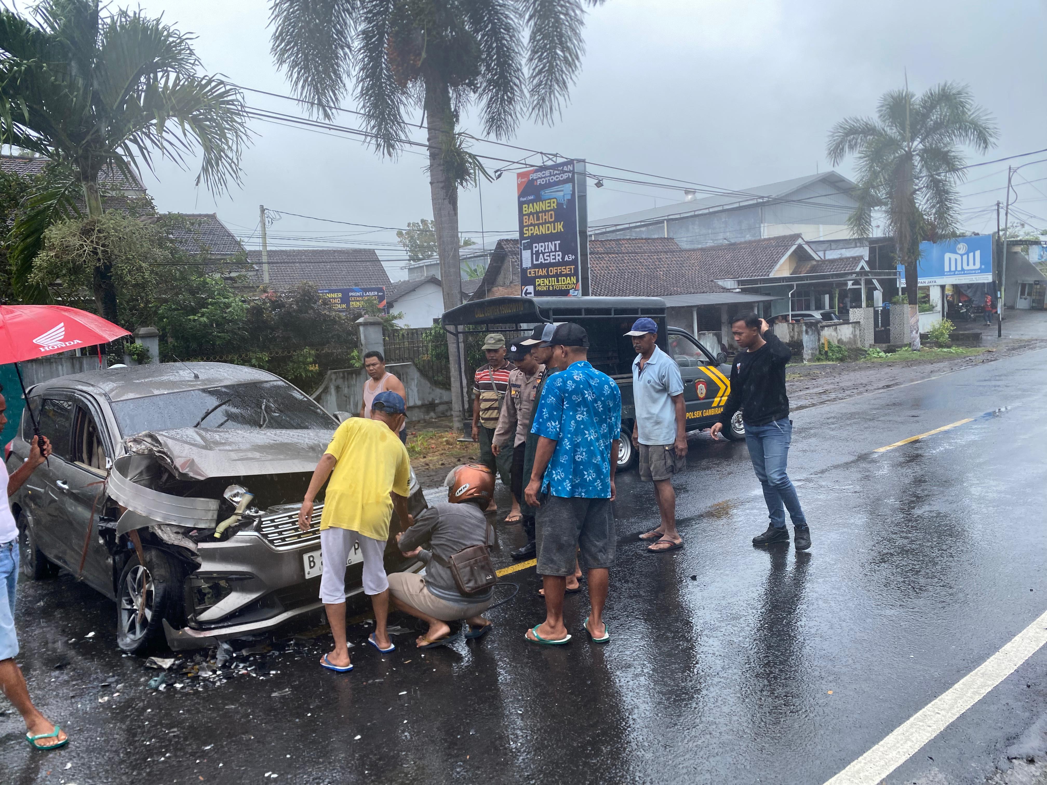 Warga dan polisi mengevakuasi mobil Suzuki Ertiga yang rusak parah akibat tabrakan beruntun di jalan raya Dusun Glowong, Desa Wringinagung, Kecamatan Gambiran.