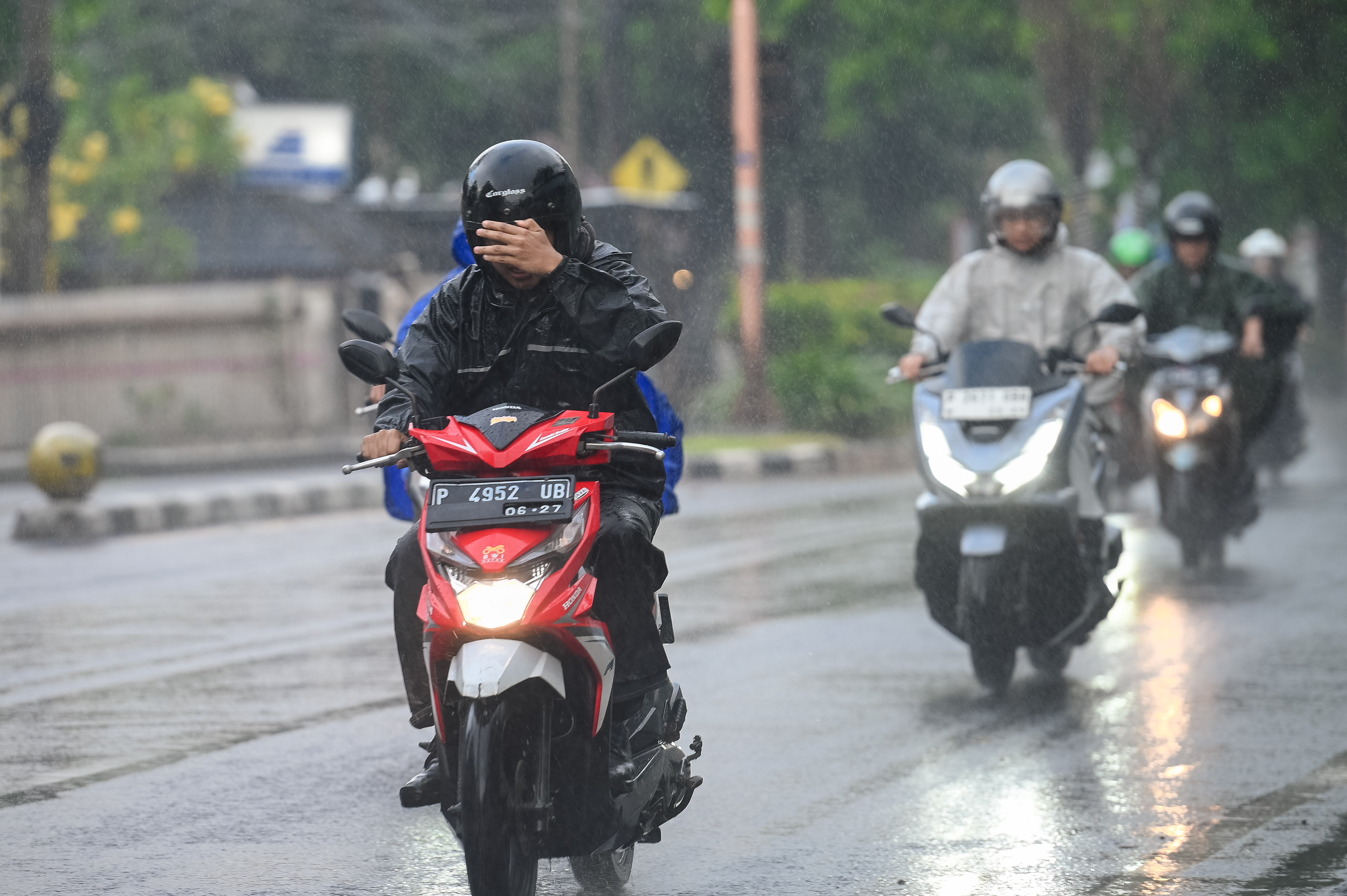 HUJAN DI MUSIM KEMARAU: Pengendara sepeda motor menangkis air hujan dengan tangan agar tak mengenai mata saat melintas di Jalan Yos Sudarso Banyuwangi pekan lalu (9/9).