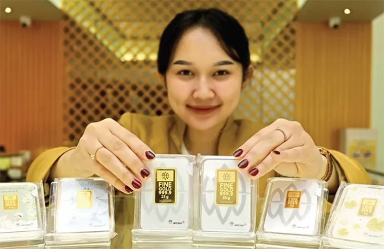 Ariani Dewi menunjukkan logam mulia produk Antam di salah satu pusat perbelanjaan di Surabaya beberapa waktu lalu.
