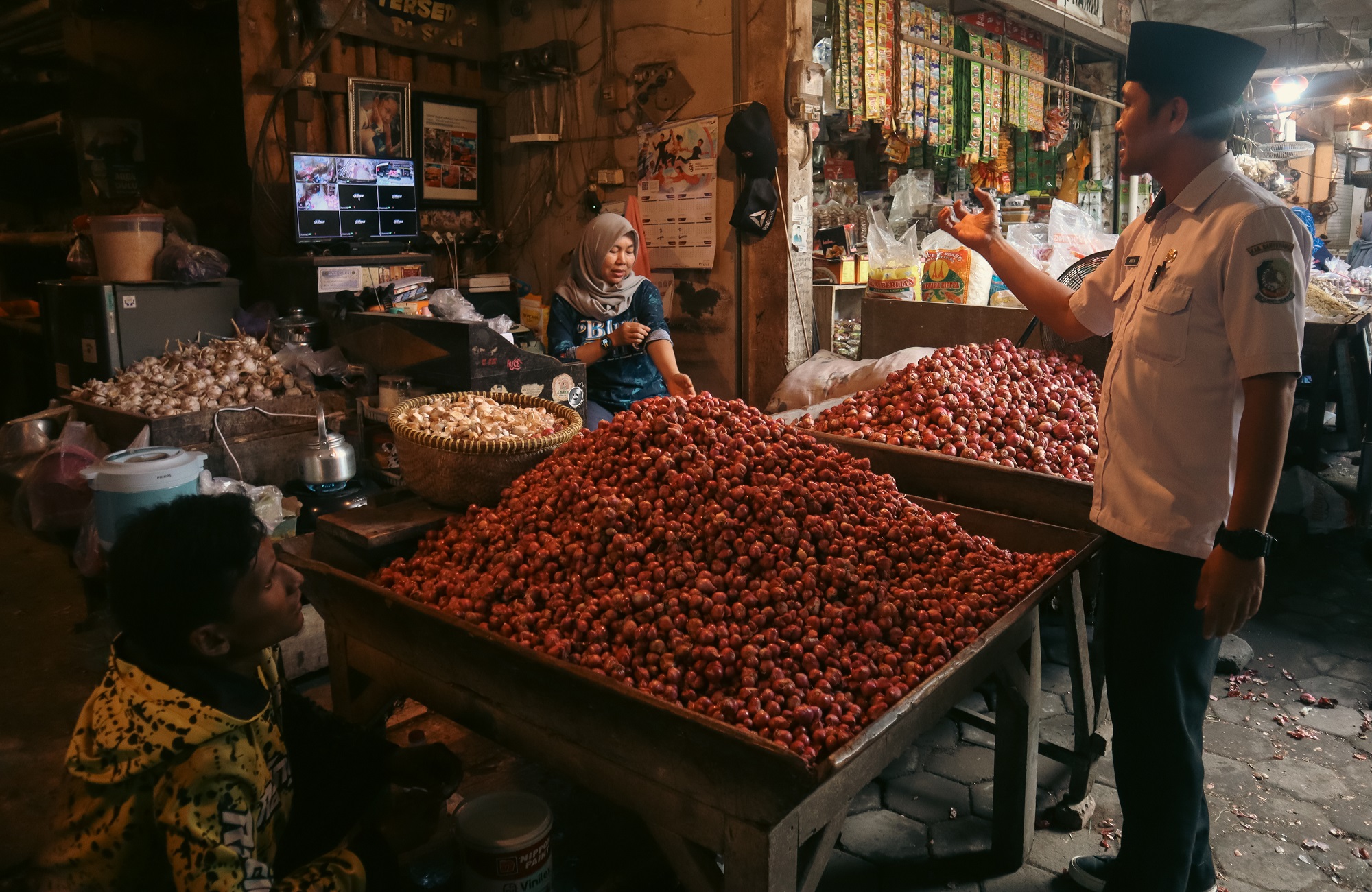 Petugas Pasar Genteng Arif Kurniawan mengecek harga bawang merah di lapak salah satu pedagang.