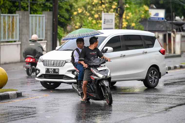 PAKAI PAYUNG: Warga mengendari sepeda motor saat gerimis melanda kawasan Jalan Yos Sudarso Banyuwangi beberapa hari lalu (9/9).