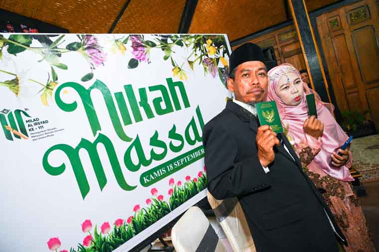 Salah satu pasangan peserta nikah massal menunjukkan buku nikah usai menjalani akad nikah dan seremoni pernikahan di kantor Disbudpar Banyuwangi, Kamis (18/9).