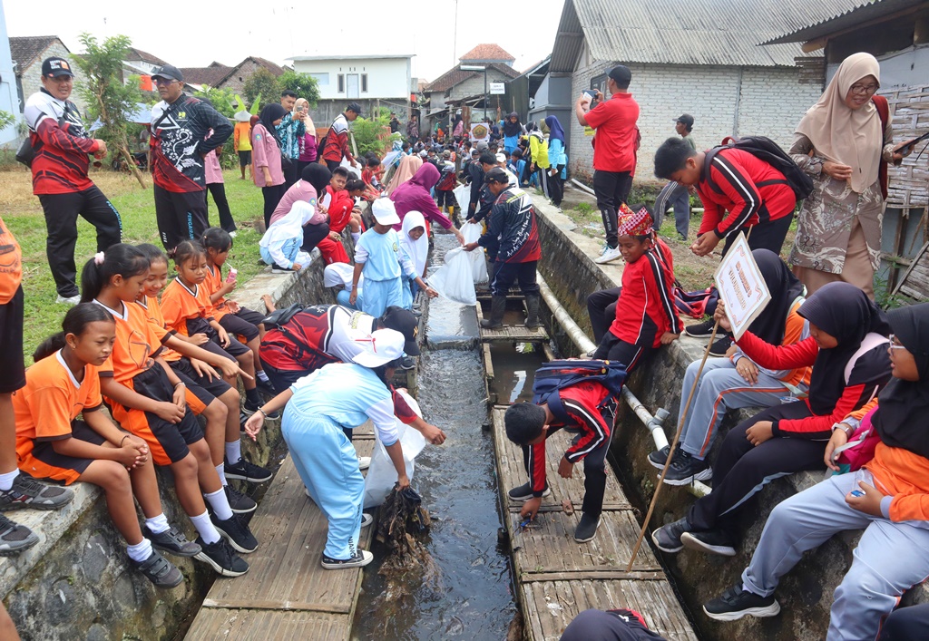 Para siswa membantu petugas Korsda Glenmore bersih-bersih saluran di Desa Sepanjang, Kecamatan Glenmore, Kamis (2/10).