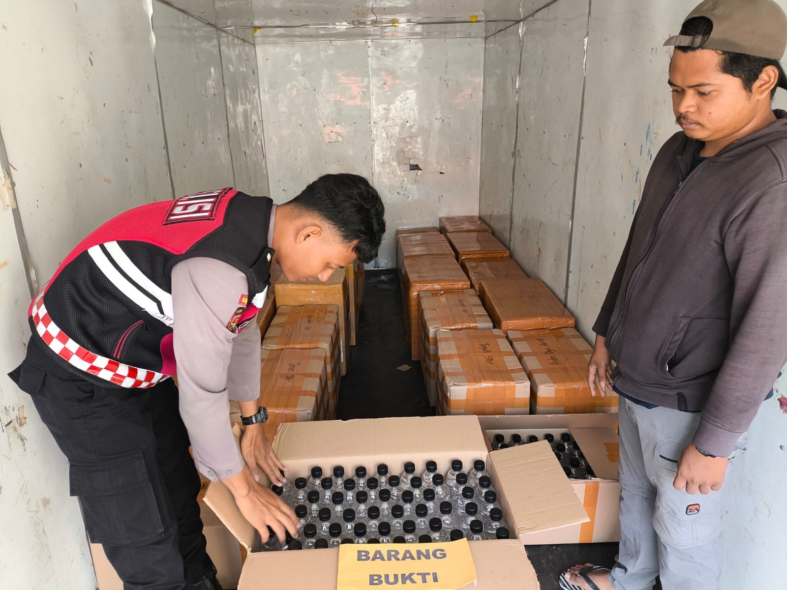 Tim Patroli Perintis menghitung botol miras jenis arak yang diangkut truk di Mapolresta Banyuwangi, Rabu (8/10/2025).
