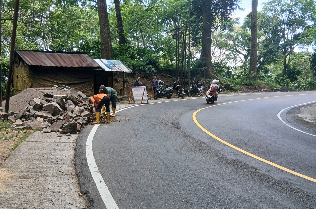 Pekerja menurunkan material di jalur Gumitir.