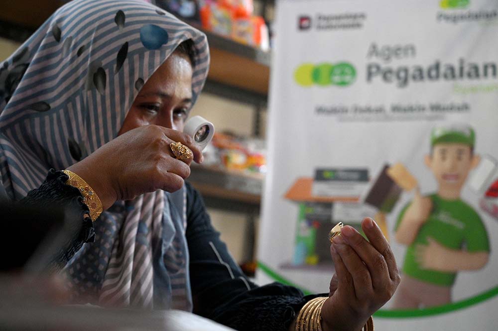 Sumiyati (47), Agen Pegadaian Toko Buksum di Desa Pesucen, Kecamatan Kalipuro, Kabupaten Banyuwangi mengecek keaslian perhiasan emas milik nasabah.