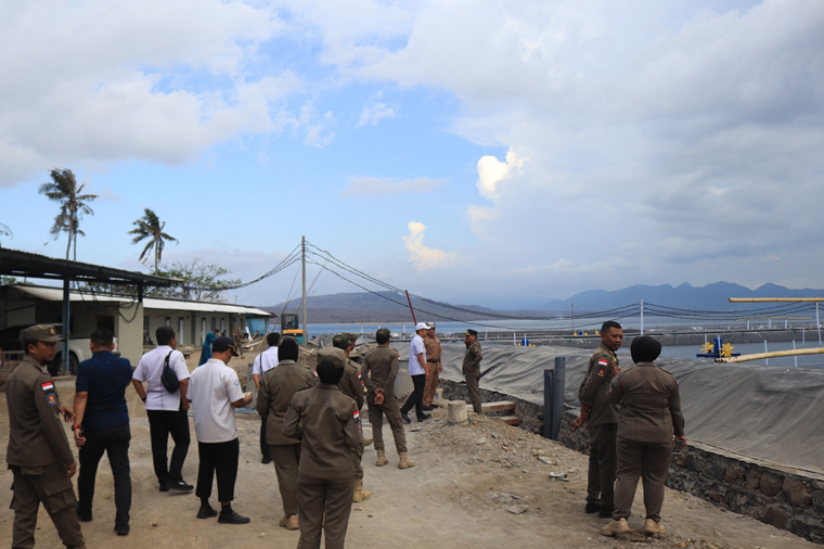 Anggota Satpol PP Banyuwangi memasang plang pemberhentian pembangunan tambak di Dusun Selogiri, Desa Ketapang, Kecamatan Kalipuro.