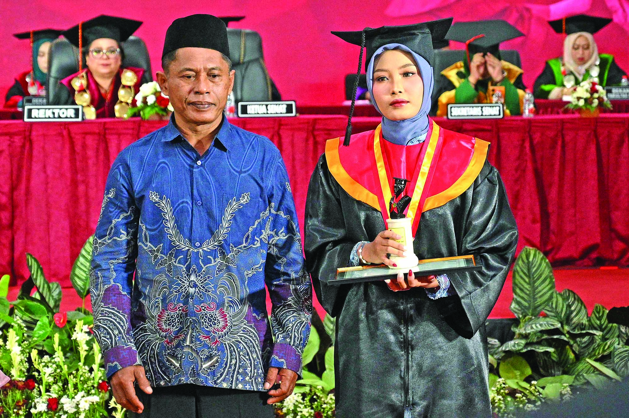 BANGGA BERCAMPUR HARU: Erlina Anjarrini didampingi sang ayah memegang piala dan sertifikat penghargaan wisudawan lulus tercepat di auditorium Untag Banyuwangi pada Sabtu (18/10).