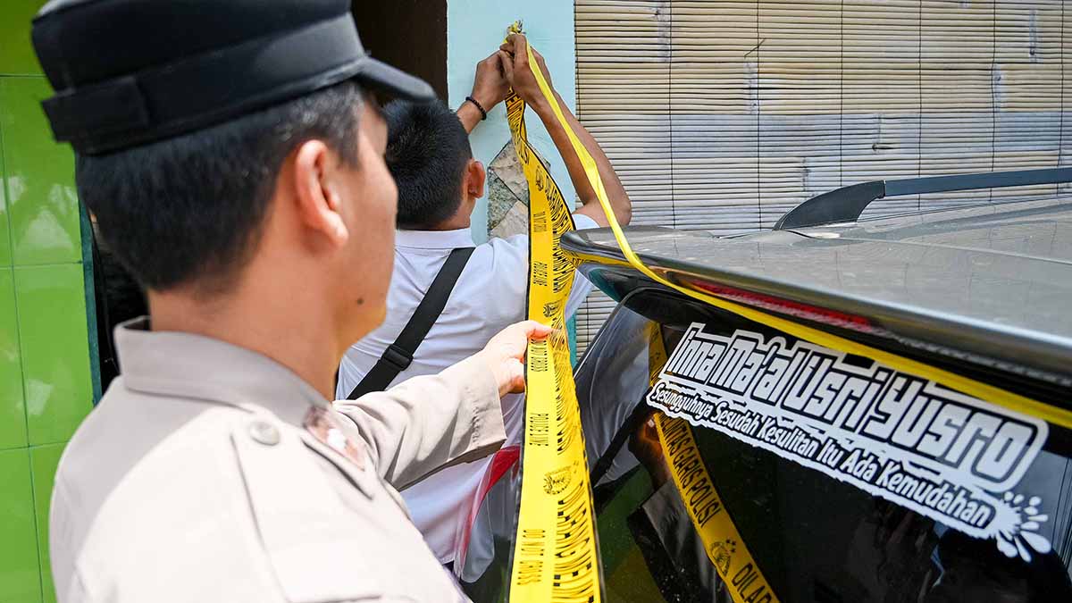 Polisi memasang garis polisi di lokasi pembunuhan istri oleh suami di Panderejo Banyuwangi, Senin pagi (20/10).
