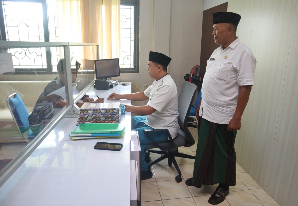 Staf di kantor Kecamatan Genteng bertugas menggunakan atribut santri.