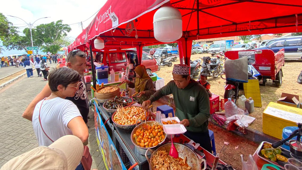 OMZET MENINGKAT: Wisatawan mancanegara berbelanja makanan ringan di stan UMKM Gandrung Sewu di kawasan Marina Boom, Sabtu (25/10).