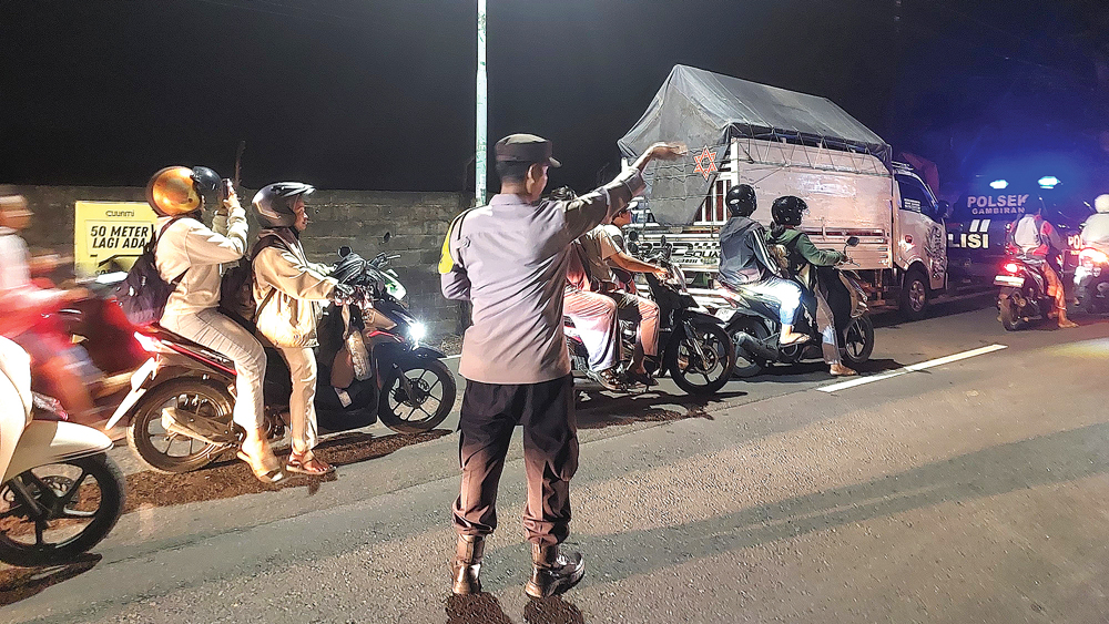 Anggota Polsek Gambiran sedang mengatur lalu lintas usai tabrakan antara mobil pikap muatan jeruk dengan Kijang Innova, Kamis (30/10) malam.