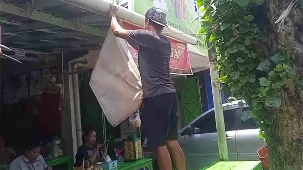 Pencopotan spanduk di sebuah warung bakso di Kota Solo.