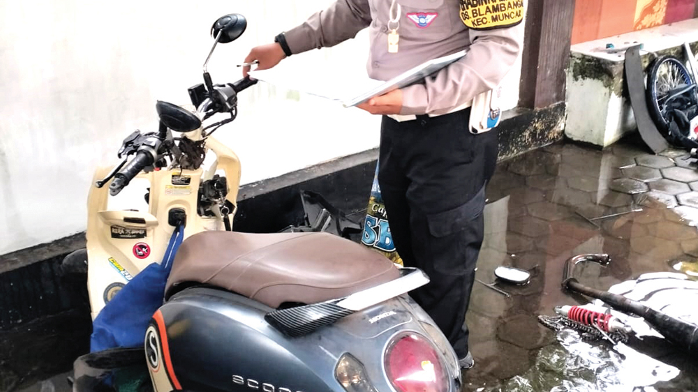BARANG BUKTI: Anggota Unit Lantas Muncar memeriksa sepeda motor Honda Scoopy yang terlibat kecelakaan di Jalan Raya Sraten pada Senin (10/11).