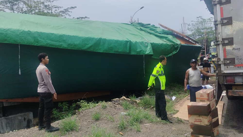 ISI MINYAK GORENG: Muatan truk tronton yang terguling di jalan raya Desa Alasrejo dipindah ke truk lain, Rabu sore (12/11).