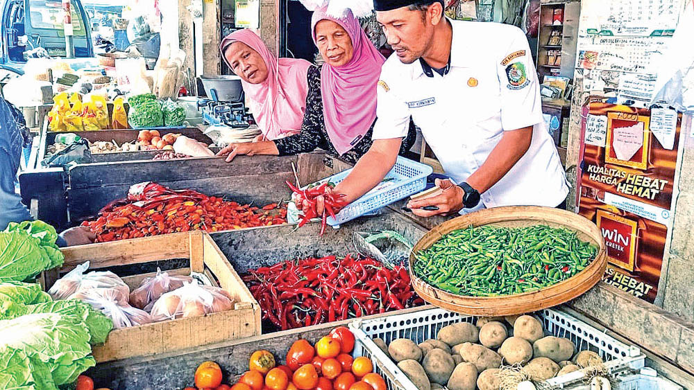 PANTAU HARGA: Petugas Pasar Genteng 1 Arif Kurniawan mengecek harga jual komoditas di pasar, Selasa (11/11).