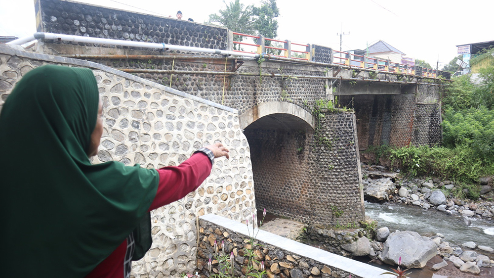 Asiah menunjukkan bagian fondasi Jembatan Misjah penghubung Desa Sumberbulu dan Desa Parangharjo, Songgon, yang rompal akibat tergerus aliran sungai, Jumat (14/11).