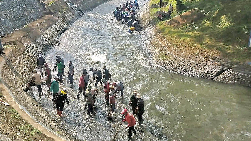 GOTONG ROYONG: Petugas membersihkan sedimen di Bendung Setail Teknik, Dusun Maron, Desa Genteng Kulon, Kecamatan Genteng, Jumat (14/11).