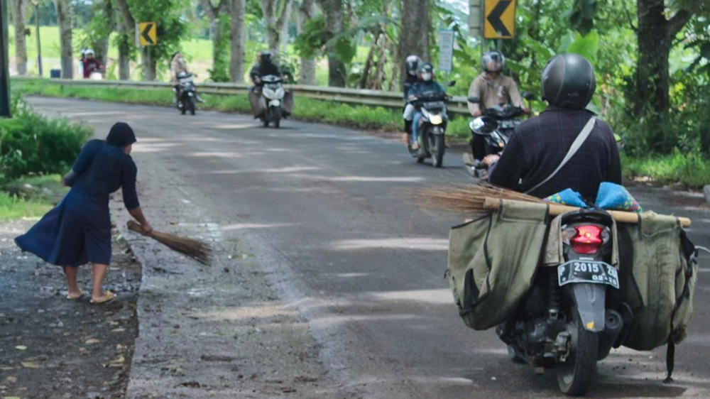 Warga bersih-bersih jalan raya di sekitar Jembatan Mayit perbatasan Karangsari, Sempu dan Genteng Wetan, Genteng, Jumat (14/11).